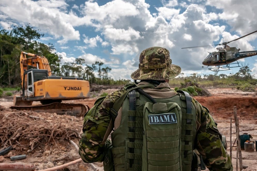 Soldado do ibama e helicóptero de fiscalização ambiental trabalhando em uma área de preservação